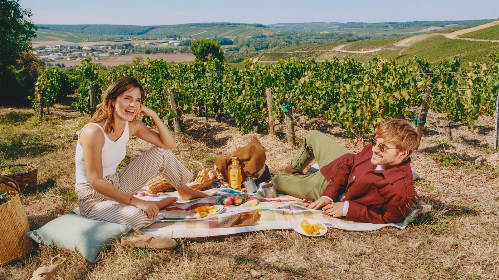 Emma and Alex Watson tasting their Renais gin while sitting on a picnic blanket with various foods in a vineyard